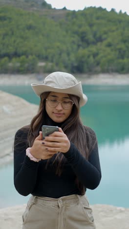 young woman taking selfies by a beautiful turquoise lake