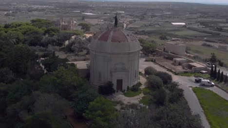 drone shot revealing a chapel on top of a hill in green fields