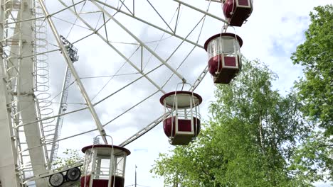 cabins of rotating ferris wheel against cloudy sky