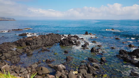 Slow-motion-static-close-up-shot-of-rough-ocean-waves-crushing-against-the-volcanic-rocky-coastline