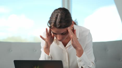 Overworked-young-successful-businesswoman-working-on-laptop-in-home-office-suffers-from-headaches