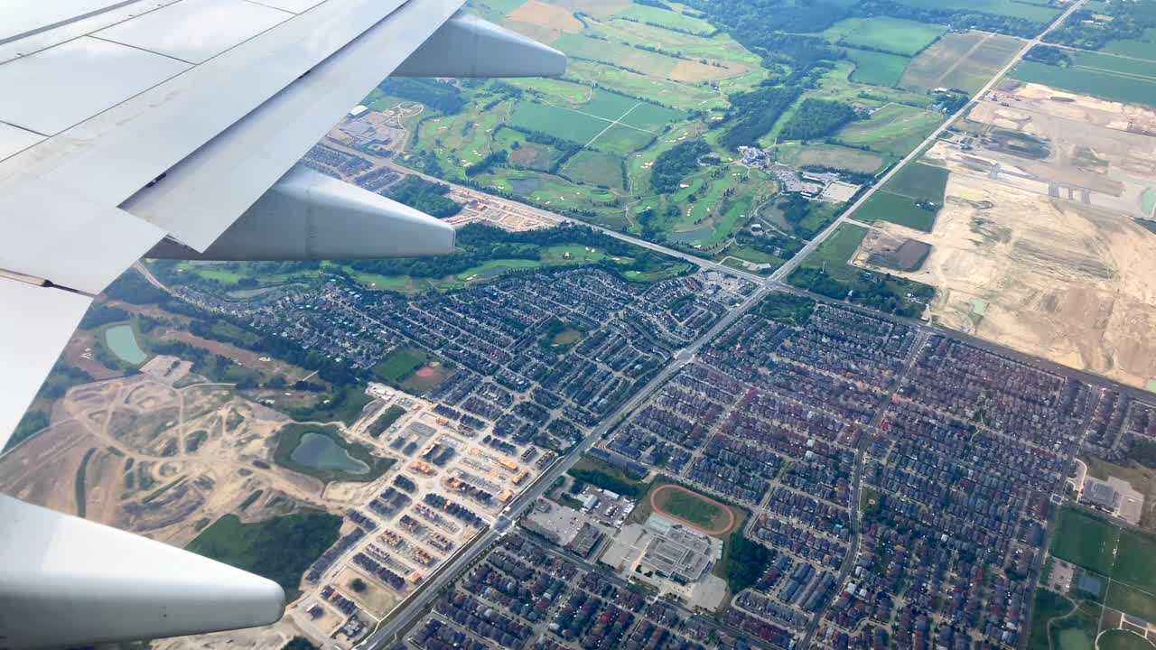 Airplane flying over new residential housing developments in urban sprawl from city into farmlands