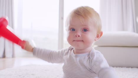 niño pequeño blanco jugando y mirando a la cámara, de cerca
