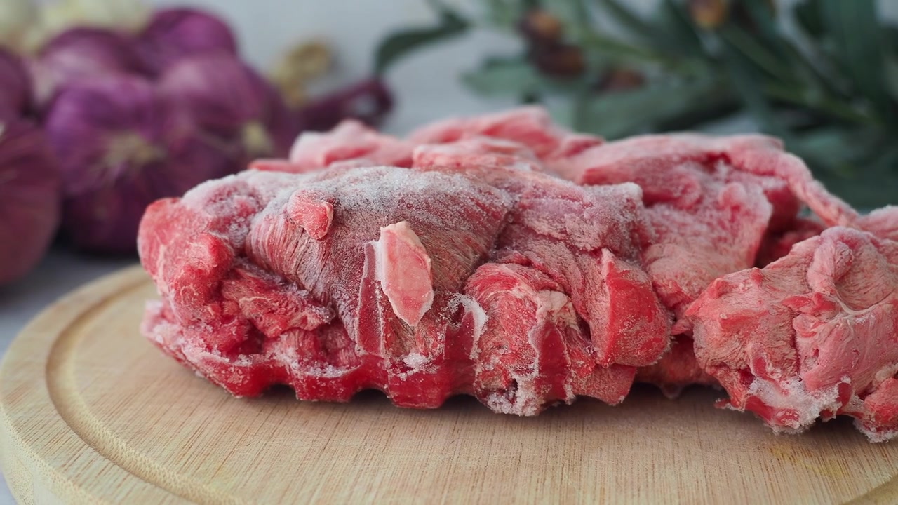 Tampak Dekat Daging Merah Mentah Beku di Atas Talenan Kayu