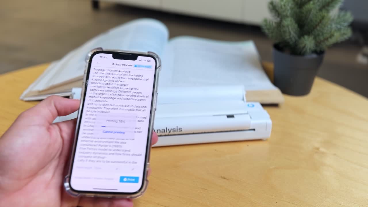 Closeup of hand using smartphone with print preview app beside portable document scanner and book on desk. Great for business, education, technology, and productivity themes
