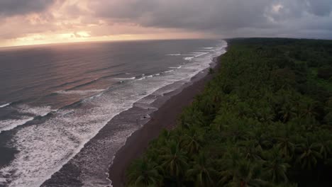 Beautiful-4K-UHD-aerial-drone-shot-of-a-tropical-Pacific-paradise-beach-sunset-at-Jaco,-Costa-Rica,-with-waves,-palm-trees-and-sand