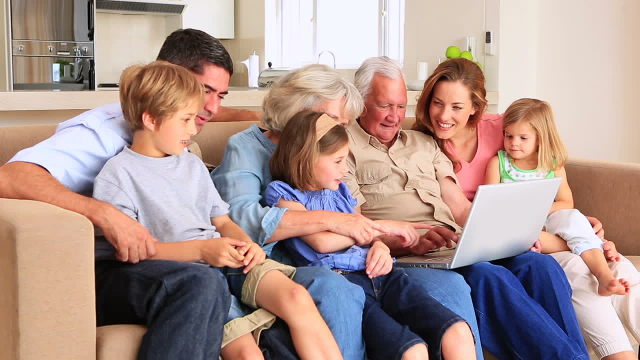Extended family using laptop together on couch