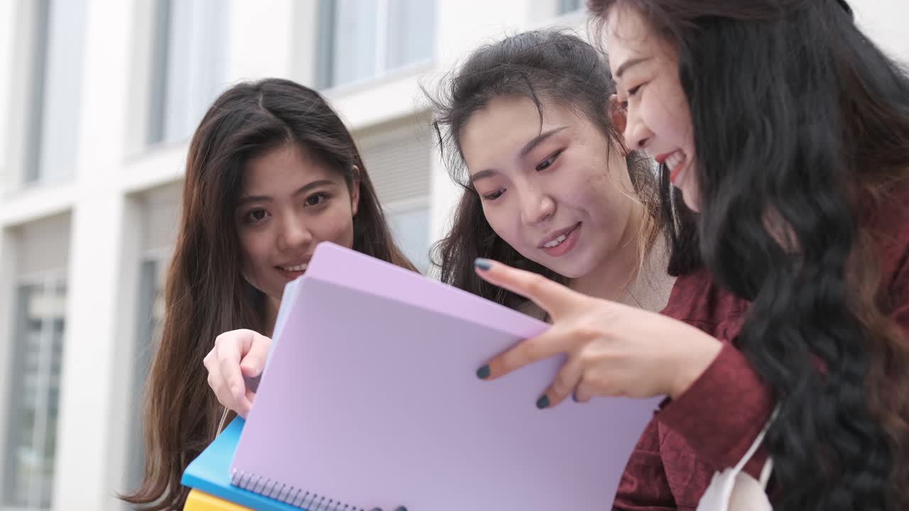 Portrait of three asian girl students talking at break time sitting on campus