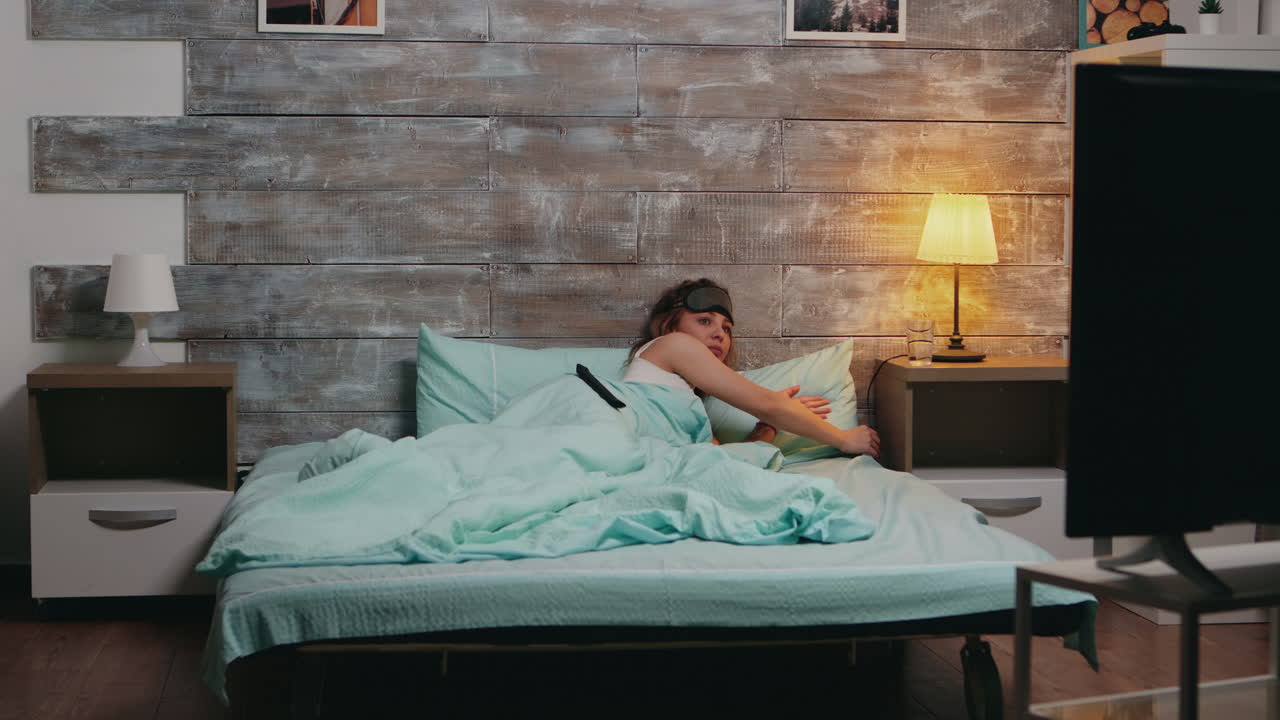 잠옷을 입은 아름다운 여성이 방에서 불을 끄고 있습니다.