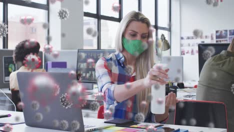 Animation-of-virus-cells-over-caucasian-businesswoman-wearing-face-mask-and-disinfecting-hands