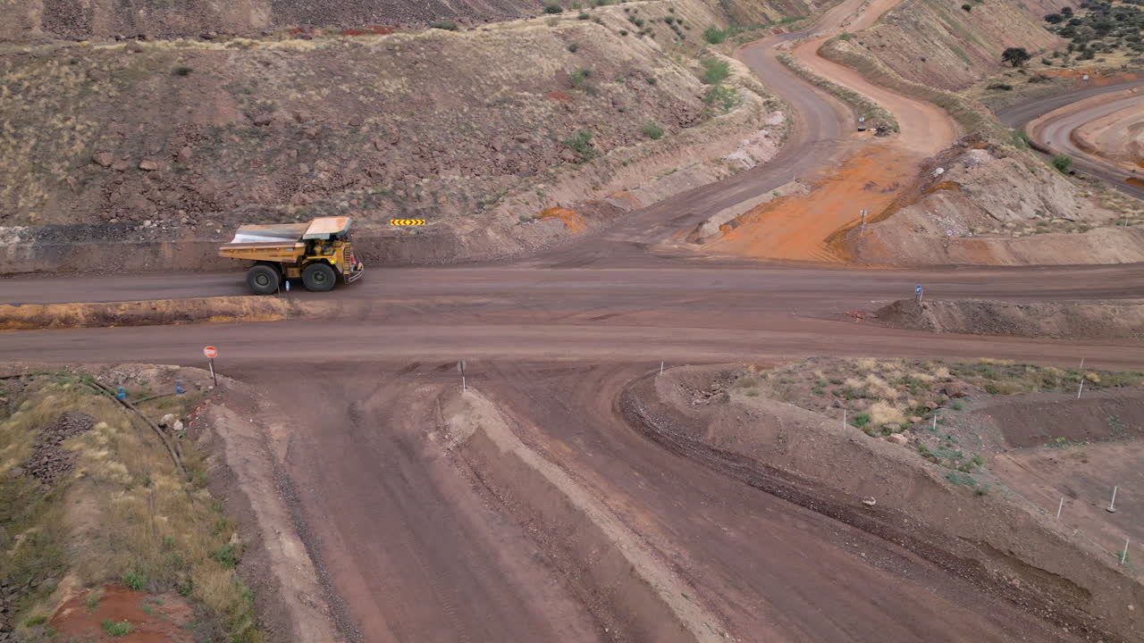 Aerial of a large tipper truck driving on a pit mine