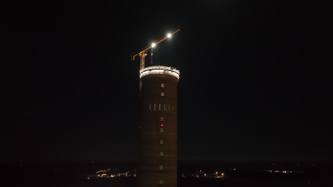 Aerial view orbiting the tallest industrial tower in Finland, during night-time