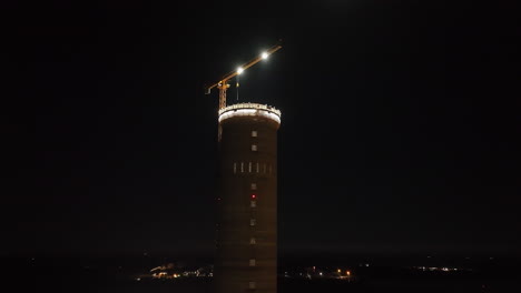 aerial view orbiting the tallest industrial tower in finland, during night-time