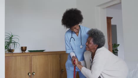 Caring-african-american-female-doctor-helping-senior-african-american-female