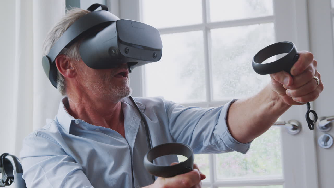 Anziano disabile in sedia a rotelle a casa che indossa un visore per la realtà virtuale e tiene in mano controller di gioco.