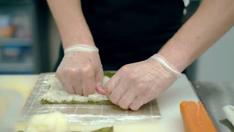 Cook-prepares-Japanese-rolls-piles-rice-on-nori-seaweed