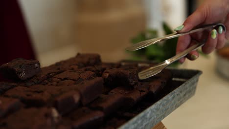 Mano-Con-Pinzas-Recogiendo-Brownie-De-Chocolate-En-La-Fiesta,-Close-up