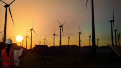 ingeniero revisando planes en una granja eólica y solar al atardecer