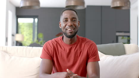 African-American-man-in-a-red-shirt-sits-comfortably-on-a-couch-on-video-call