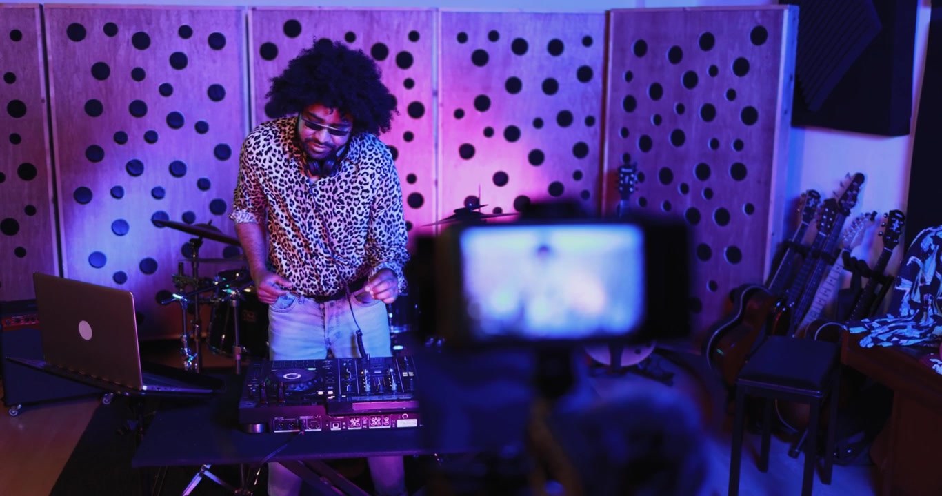 DJ con capelli afro che si prepara per una diretta streaming in uno studio musicale.