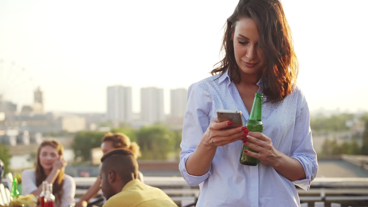 Woman on Rooftop Party with Smartphone and Beer