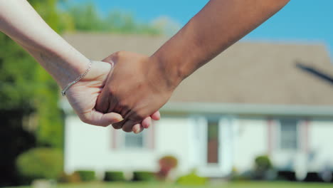 a young couple holding hands against the backdrop of their new home buying real estate concept a dre