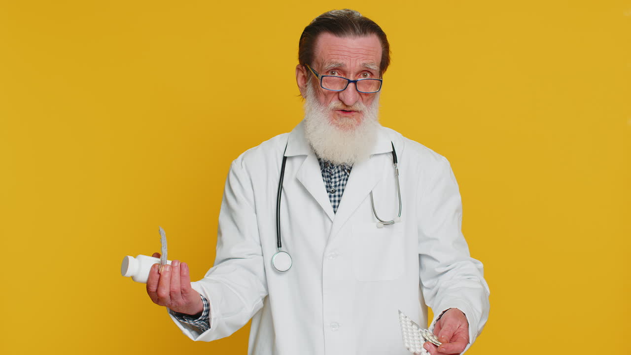 Senior doctor man show lot of tablet pills in blisters recommends drugs vitamin antibiotic treatment