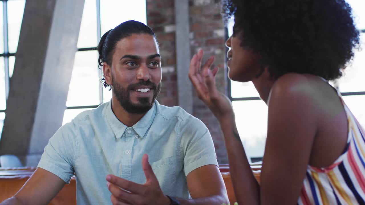 Diverse male and female colleagues sitting in cafe drinking coffee having a discussion
