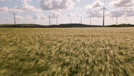 Low-flight-over-an-orange-grain-field-towards-a-wind-park-in-Germany