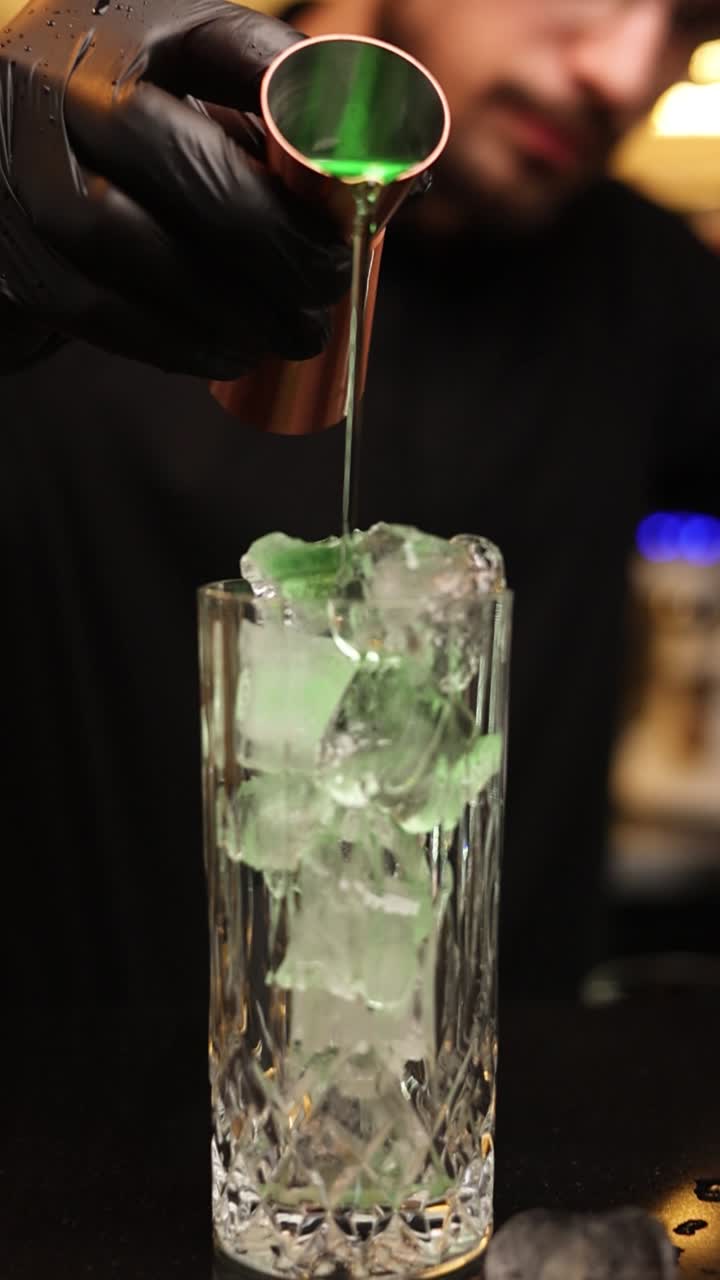 Bartender preparing a green cocktail with ice
