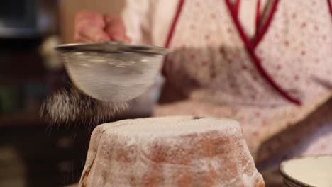 sprinkling sugar on top of a traditional slovenian dessert called potica