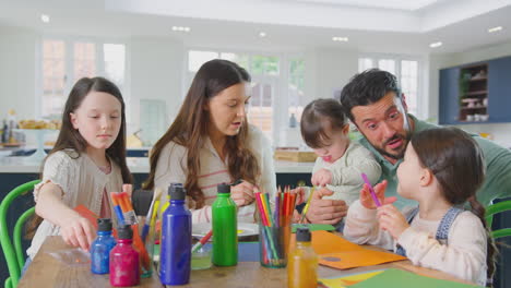 Una-Familia-Con-Una-Hija-Con-Síndrome-De-Down-Sentada-Alrededor-De-Una-Mesa-En-Casa-Haciendo-Manualidades-Haciendo-Tarjetas-Juntas