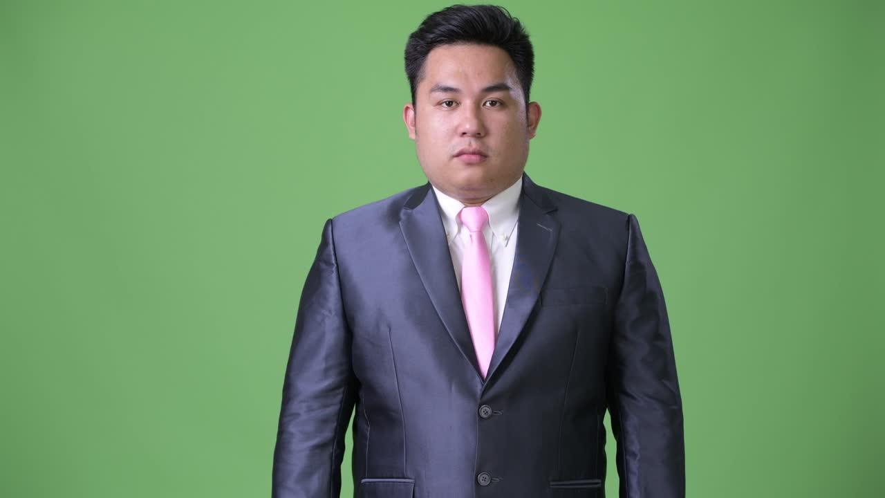 초록색 배경에 젊은 잘생긴 과체중 아시아 사업가
