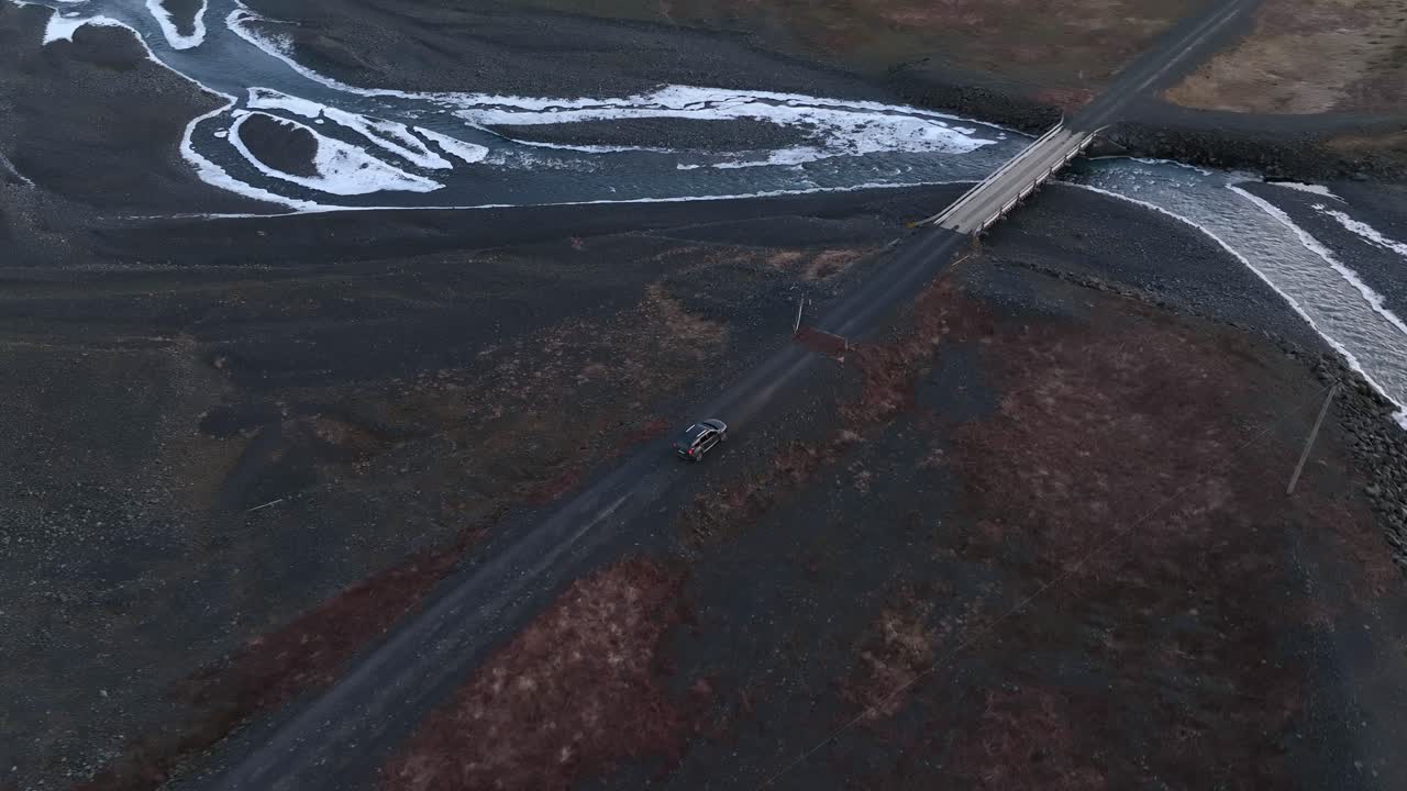 Aerial view of a car crossing a bridge over a river