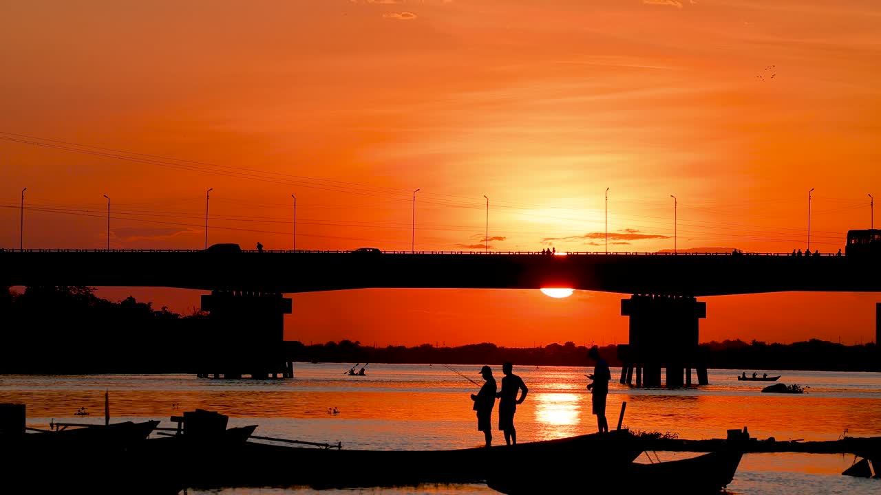 Sunset Silhouette of People Fishing Under a Bridge