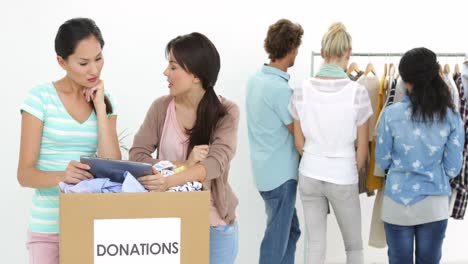 Team-of-smiling-workers-using-tablet-beside-donation-box