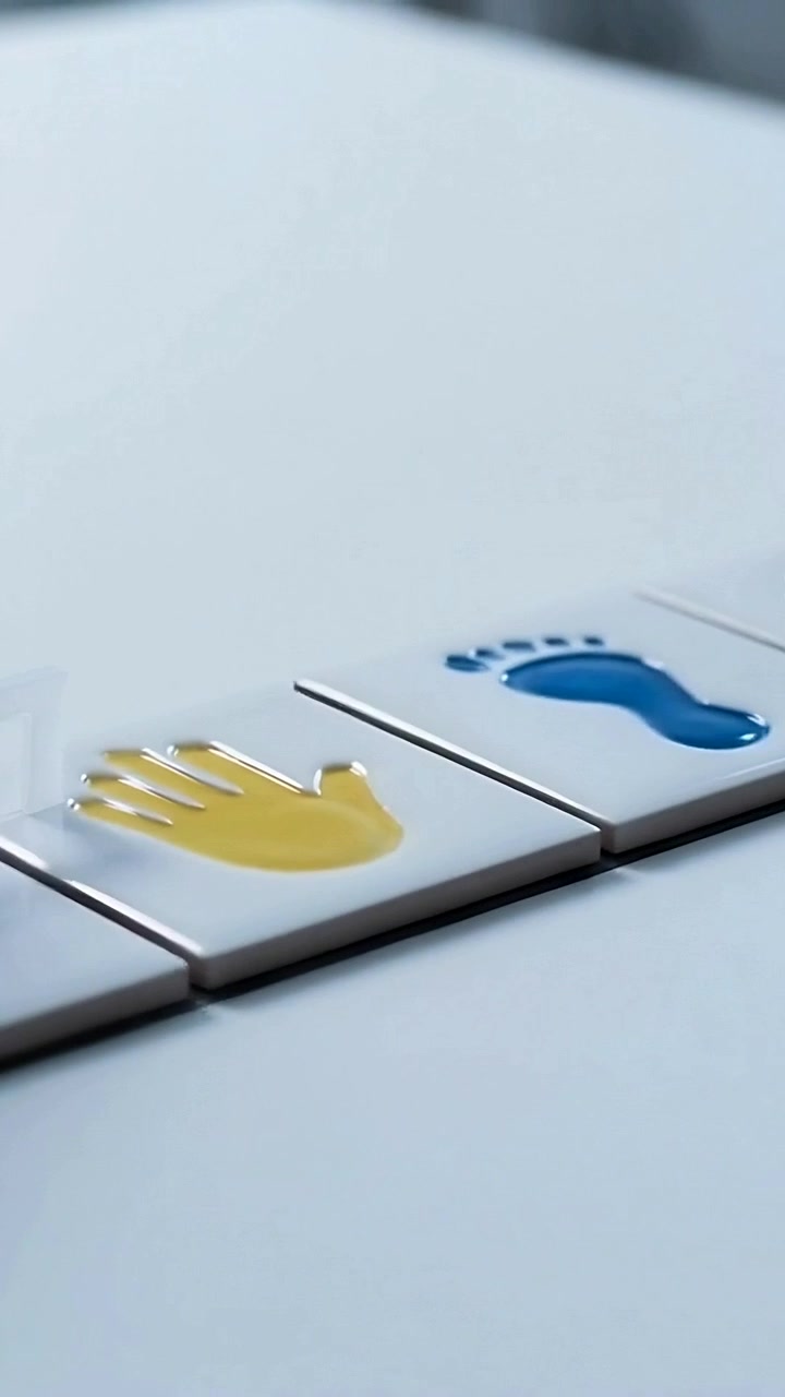 Vertical video: Reaching gloved hand placing film on white table sealing yellow hand blue footprint