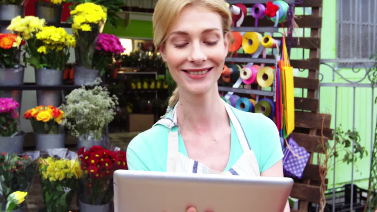 florista sonriente usando una tableta digital en la floristería