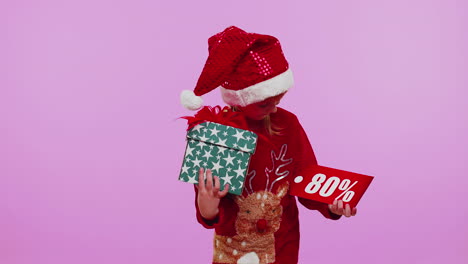 Niña-Pequeña-Con-Sombrero-De-Navidad-Mostrando-Caja-De-Regalo-Y-Nota-De-Texto-De-Banner-De-Inscripciones-De-80-Por-Ciento-De-Descuento