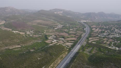 m2 motorway cutting through green hills and patchwork fields near kallar kahar, punjab, pakistan