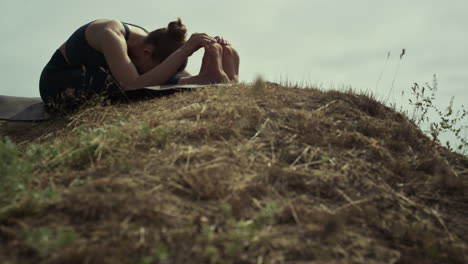 Sporty-girl-doing-gymnastics-on-beach-hill.-Woman-making-yoga-asana-outdoors.