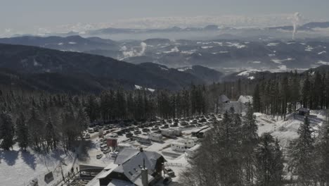 kope ski resort complex rv and car parking in the pohorje mountains with smoke in the distance, aerial dolly in reveal shot