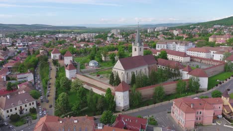 a wide aerial tracking shot reveals the well-preserved medieval fortress (cetatea) and its gothic church in the heart of the city of targu mures, transylvania, romania