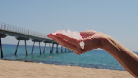 ice cubes melting in hand on a beach