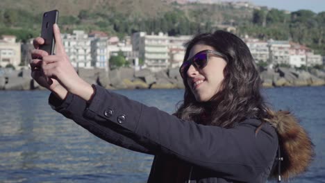 girl taking selfie and pictures near the sea