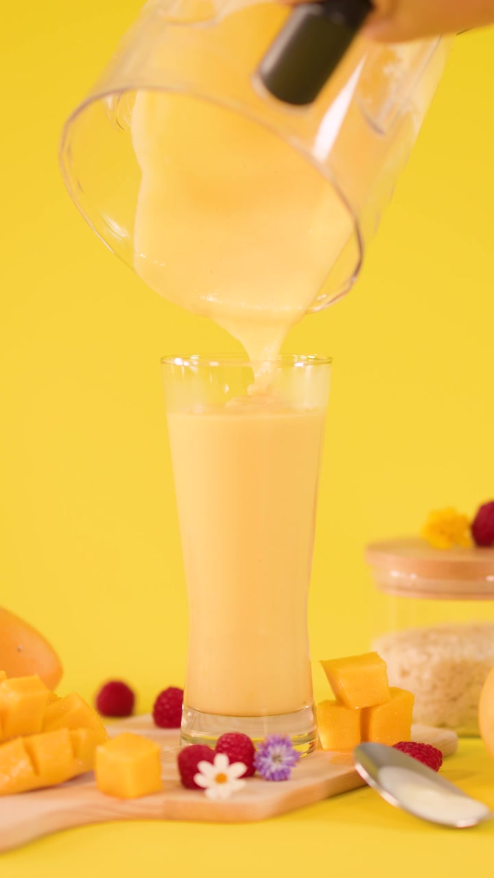 Versamento di frullato fresco di mango in un bicchiere