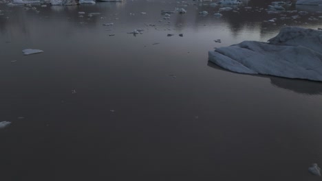 icebergs floating by iceland glacier, cinematic aerial tilt-up reveal