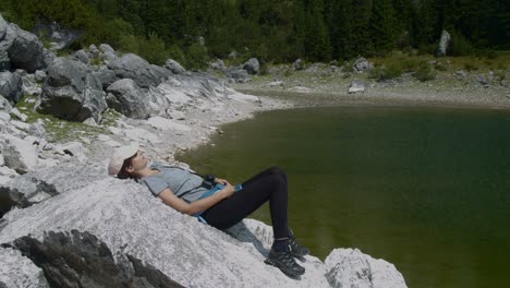 Female-relaxing-on-a-a-rock-by-the-beautiful-lake