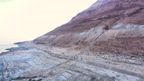 Drohnenaufnahme-Einer-Wüstenberglandschaft-Mit-Blick-Auf-Die-Küste-Des-Toten-Meeres,-Israel,-Standort-Sind-Die-Heißen-Quellen-Des-Toten-Meeres