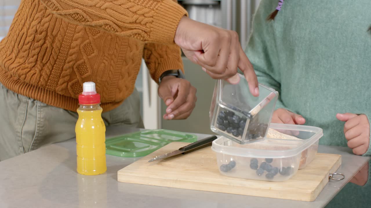 I køkkenet åbner far og datter køleskabet, pakker blåbær og juice ned i en taske og forbereder frokost.